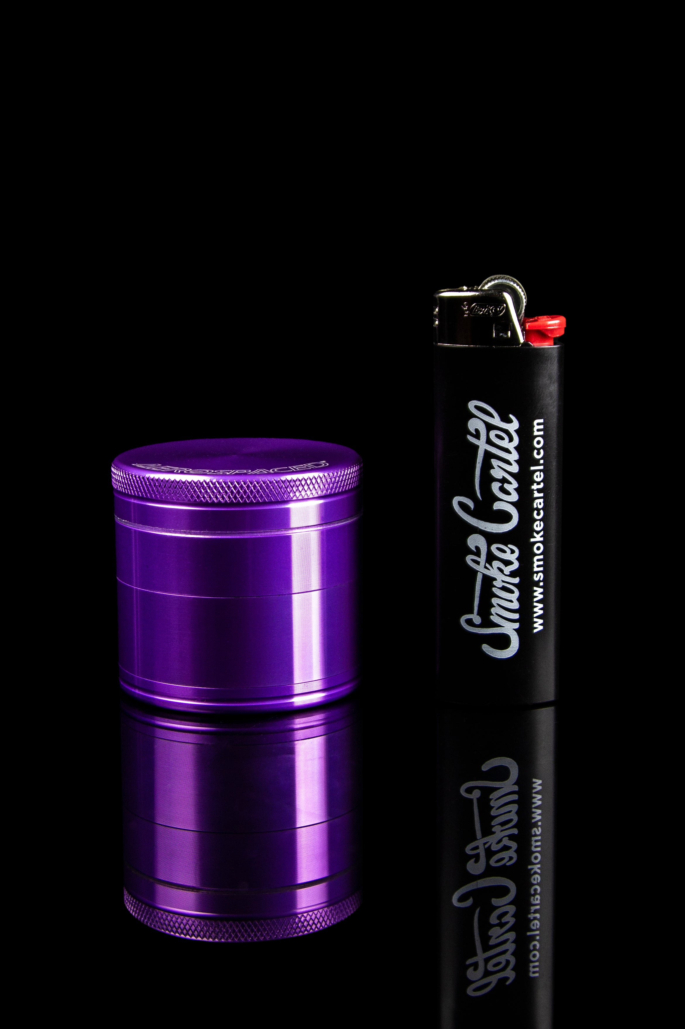 Purple cannabis grinder and branded lighter on a reflective black surface.