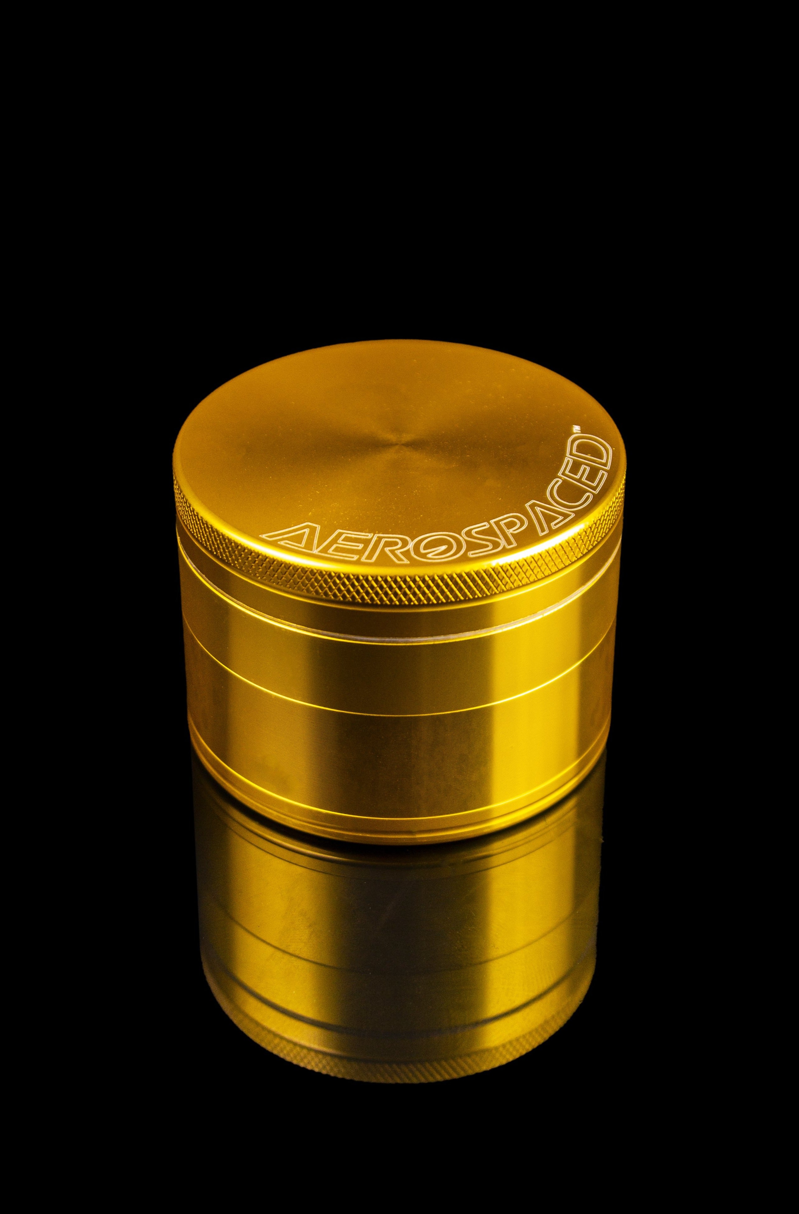Gold four-piece cannabis grinder with “AEROSPACE” branding against a black background.