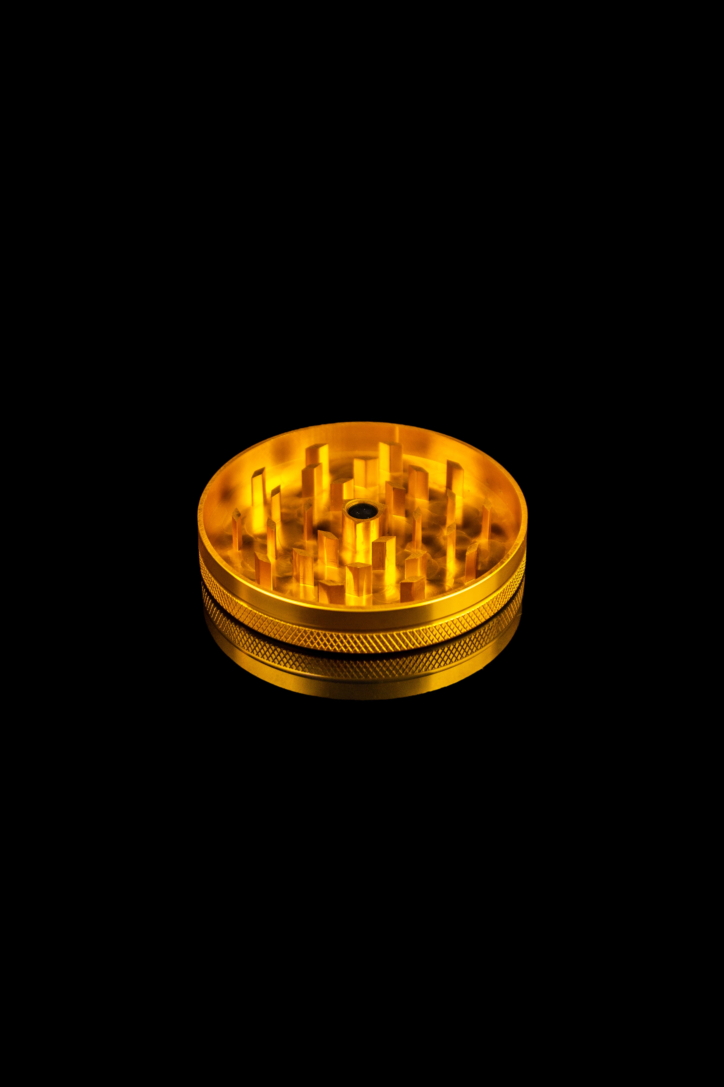 Gold cannabis grinder isolated on a black background.