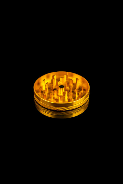 Gold cannabis grinder isolated on a black background.