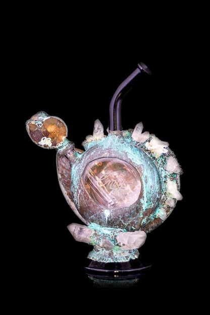 Hand-blown glass water pipe with a unique, organic shape, featuring copper-colored accents and crystalline formations, set against a black background.