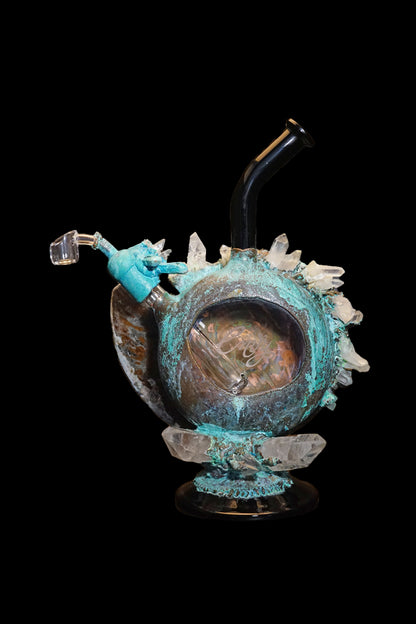 A detailed glass water pipe shaped like a pumpkin, adorned with crystal-like spikes and a turquoise-blue glaze, set against a black background.