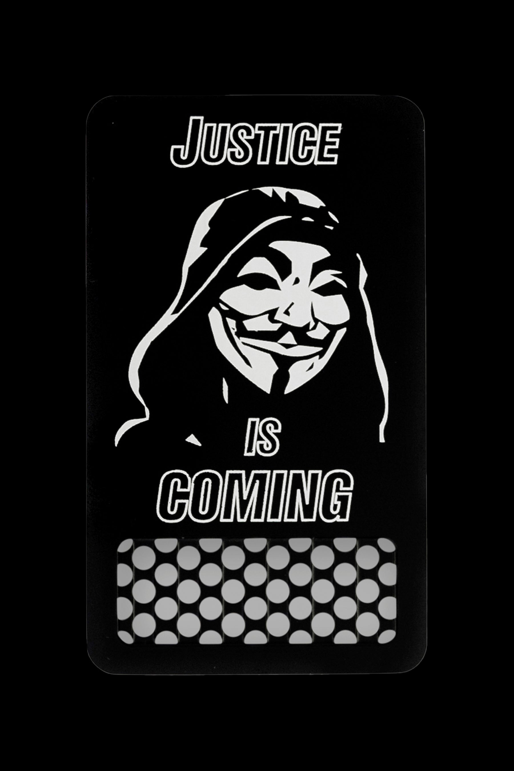 A rectangular sticker with a grayscale depiction of the Guy Fawkes mask over the text "JUSTICE IS COMING", with a pattern resembling cannabis buds at the bottom.