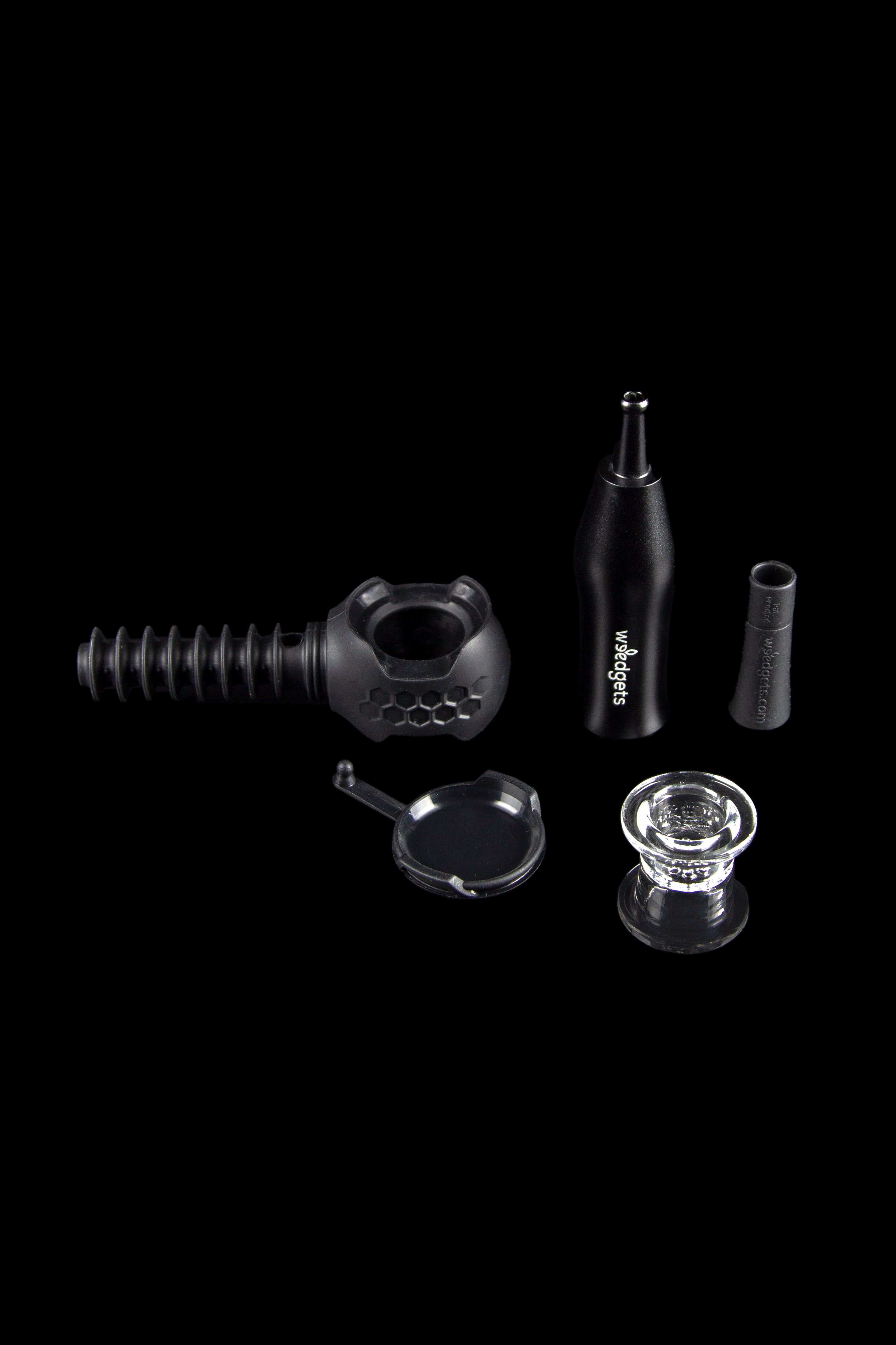 Black cannabis accessories including a water pipe, glass bowl, and silicone attachments on a dark background.