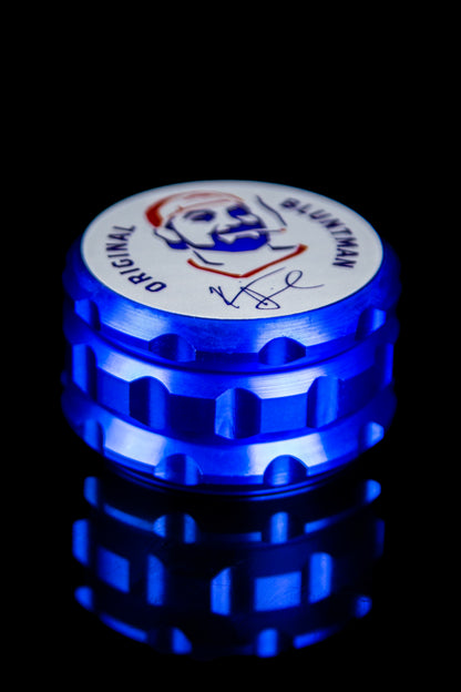 Blue metal grinder with a colorful "Original Bluntman" logo on the lid.