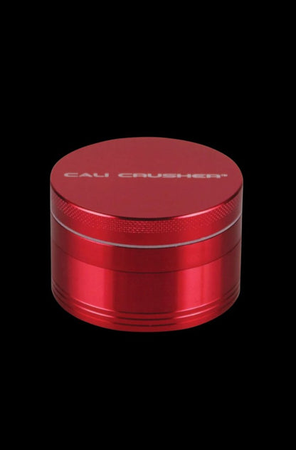Close-up of the silver Cali Crusher O.G. 4-Piece Grinder, viewed from a slight angle against a plain black background.