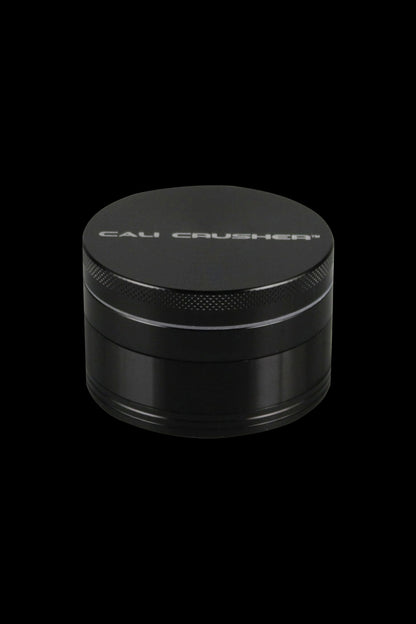 A close-up, angled view of the Cali Crusher O.G. 2.5" 4 Piece Grinder, showing its metallic, circular design.