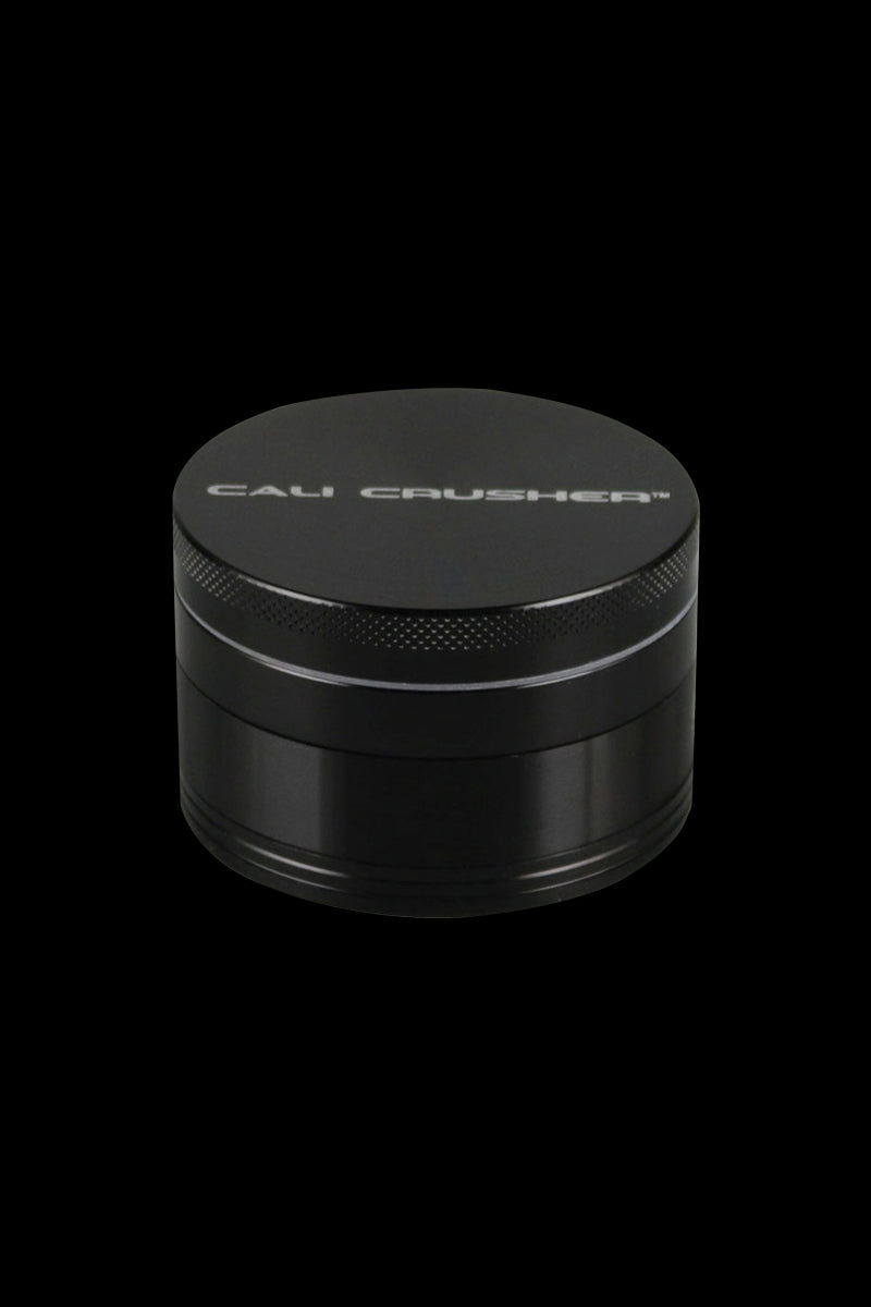A close-up, angled view of the Cali Crusher O.G. 2.5" 4 Piece Grinder, showing its metallic, circular design.