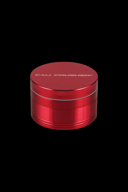 A close-up of the red Cali Crusher O.G. 2.5" 4 Piece Grinder, viewed from a slight upward angle.