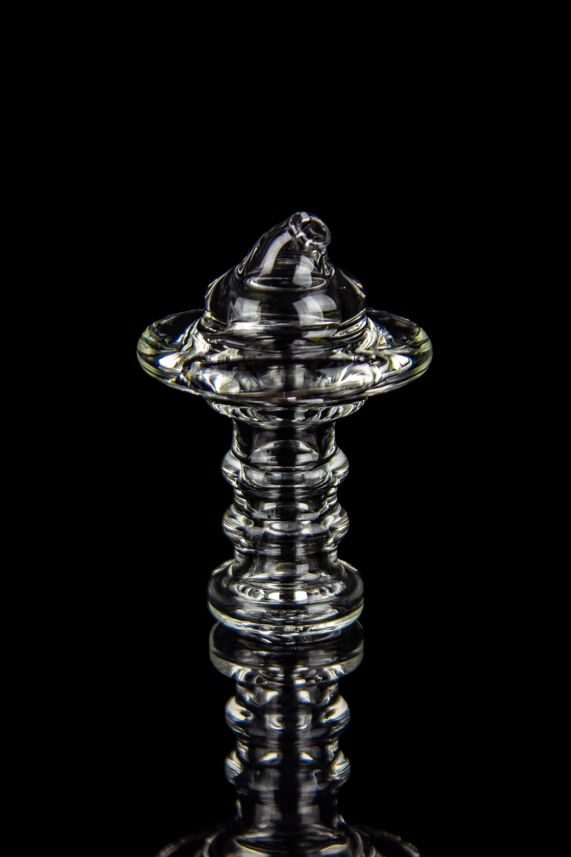 Clear glass dab rig with intricate spiraled design, isolated on black.