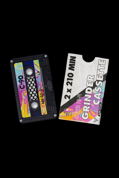 A retro-style cassette tape designed as a cannabis grinder, featuring bright purple and teal colors with text indicating it's a ""2x210 MIN GRINDER CASSETTE."""