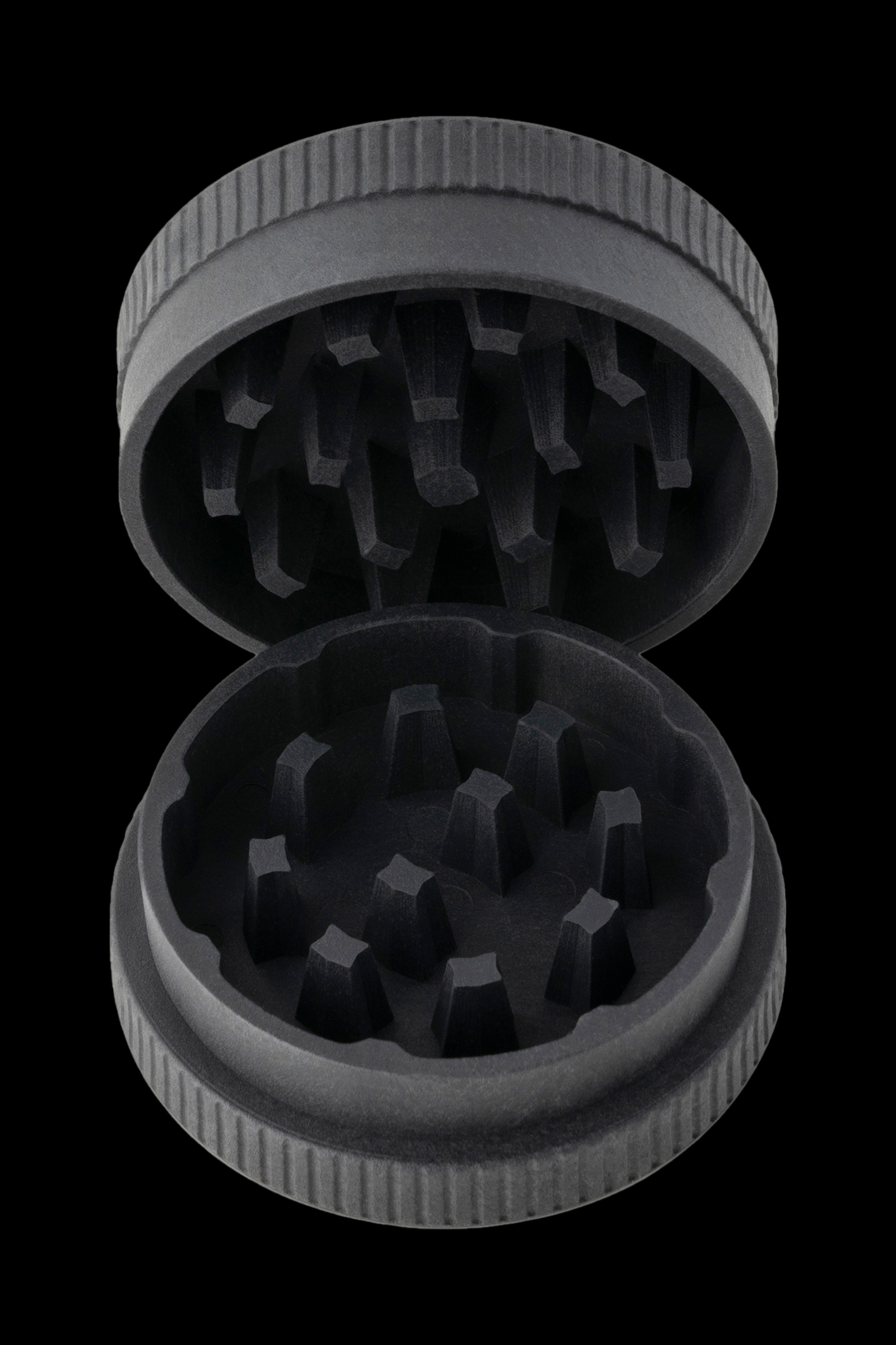 Open metal cannabis grinder with visible grinding teeth, against a black background.