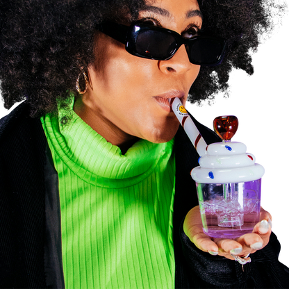 A close-up, angled view shows a person holding the Goody Cupcake Bubbler, its colorful design contrasting with their green shirt.