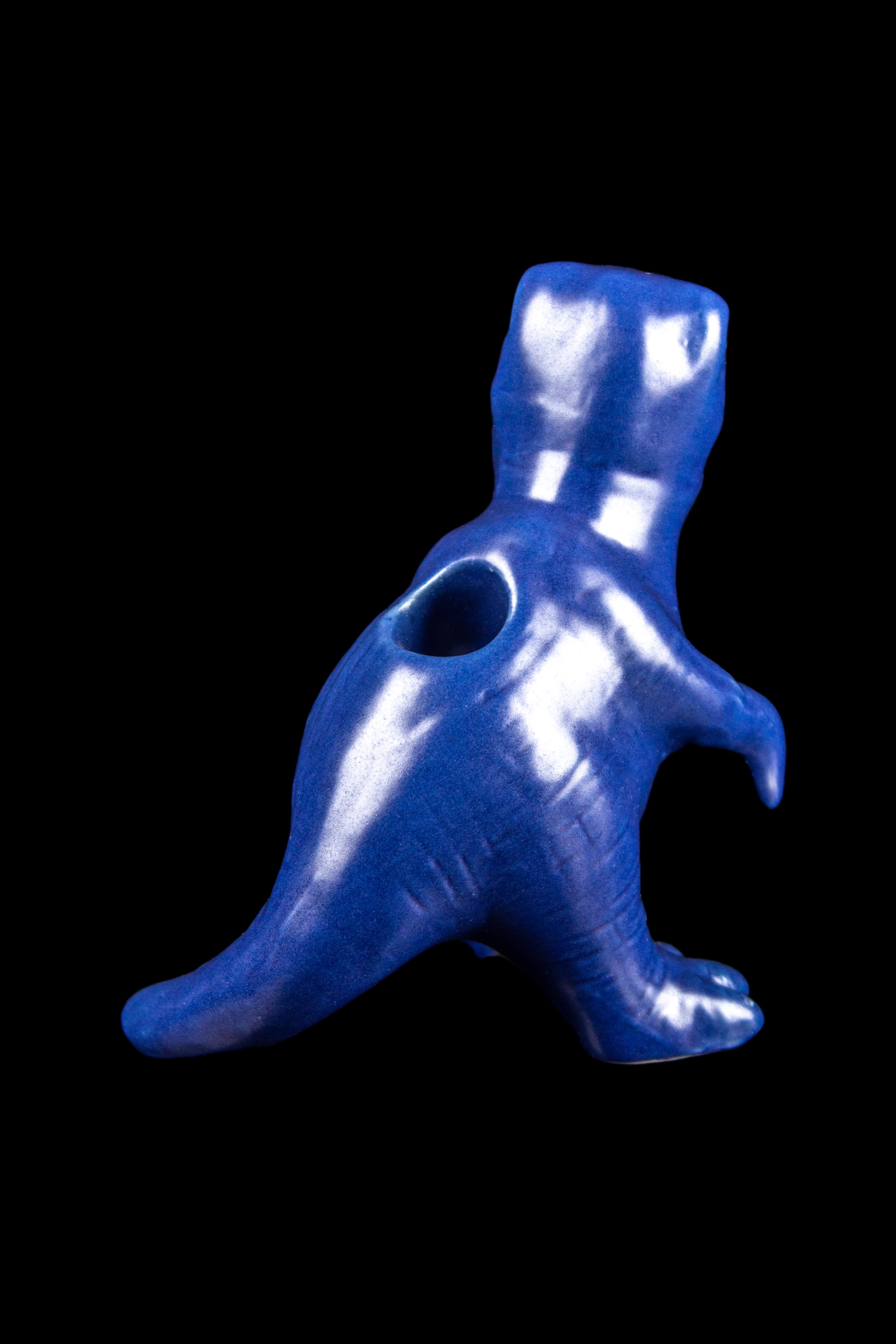 Blue dinosaur-shaped glass pipe against a black background.