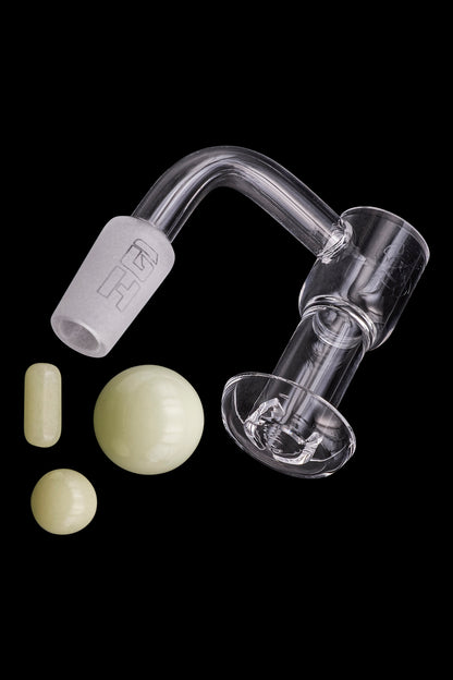 Quartz dab rig components including a banger, carb cap, and terp pearls on a black background.