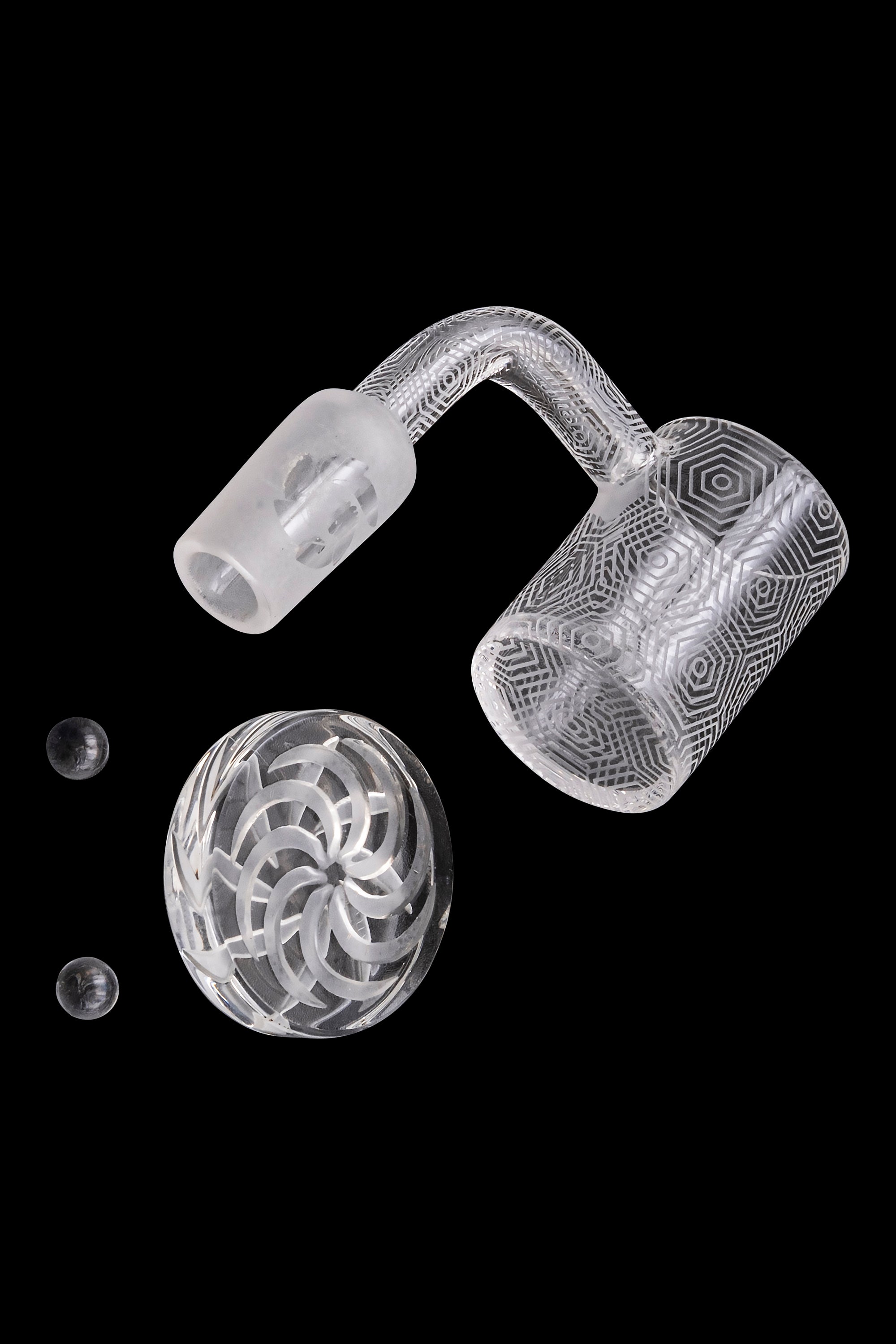 Clear glass dab rig components—including a carb cap, banger, and small glass marbles—isolated on a black background.