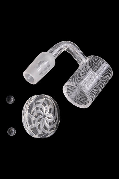 Clear glass dab rig components—including a carb cap, banger, and small glass marbles—isolated on a black background.