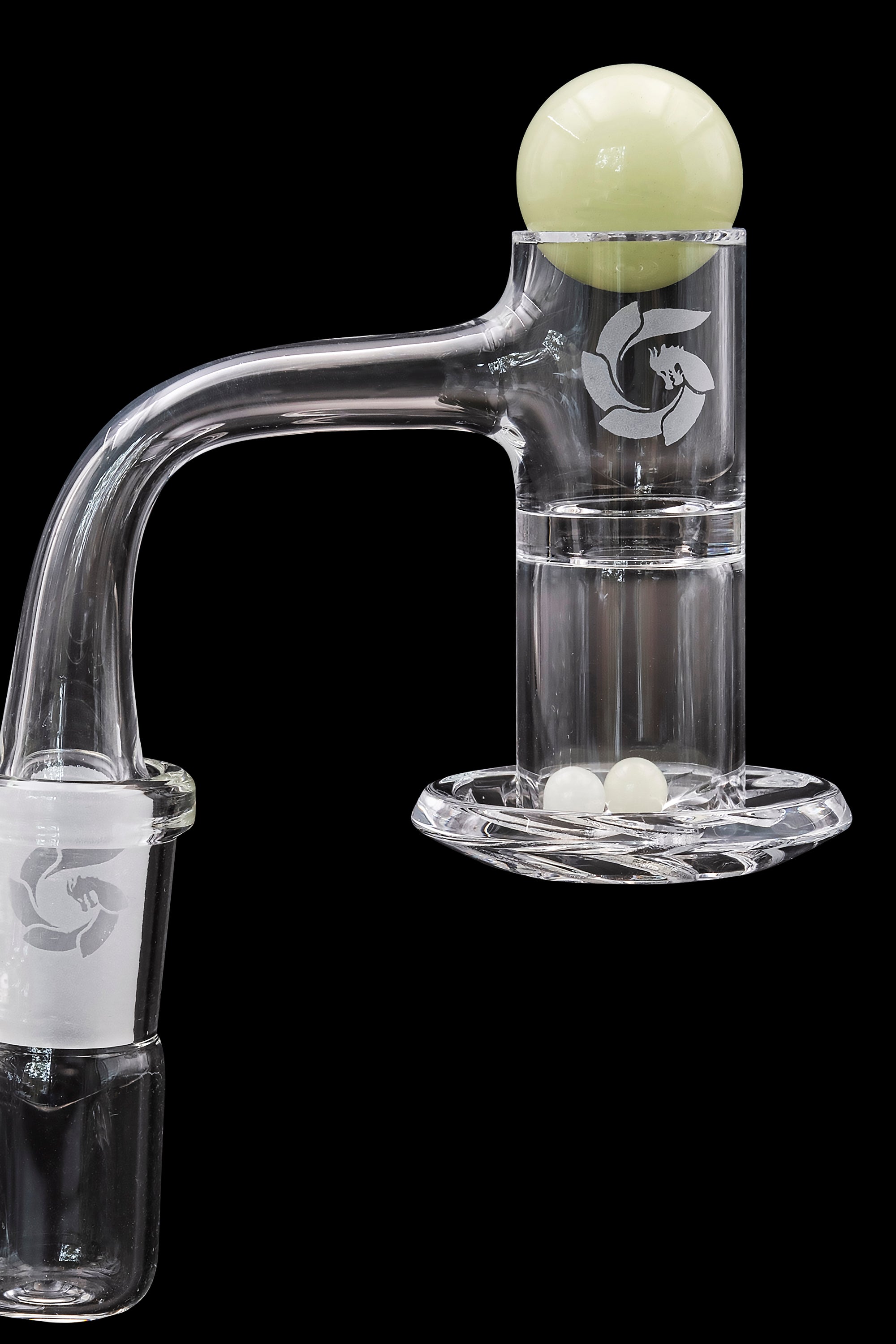 Clear glass dab rig with a spherical carb cap resting on its mouthpiece, set against a black background.