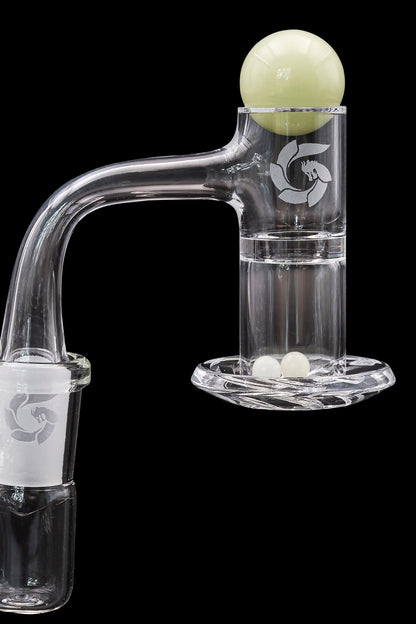 Clear glass dab rig with a spherical carb cap resting on its mouthpiece, set against a black background.