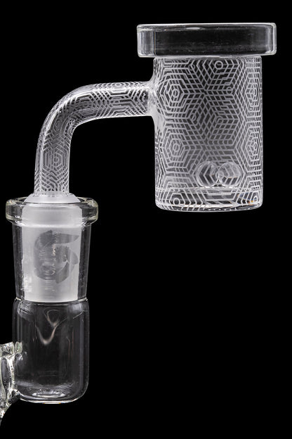 Clear glass dab rig with geometric etched design, isolated on black.