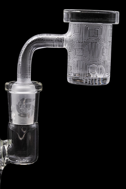 Clear glass cannabis concentrate carb cap with intricate geometric patterns, isolated on a black background.