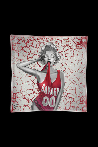A glass ashtray featuring a stylized black and white illustration of Marilyn Monroe in a red tank top with "SAVAGE" printed on it, set against a cracked red and white background.