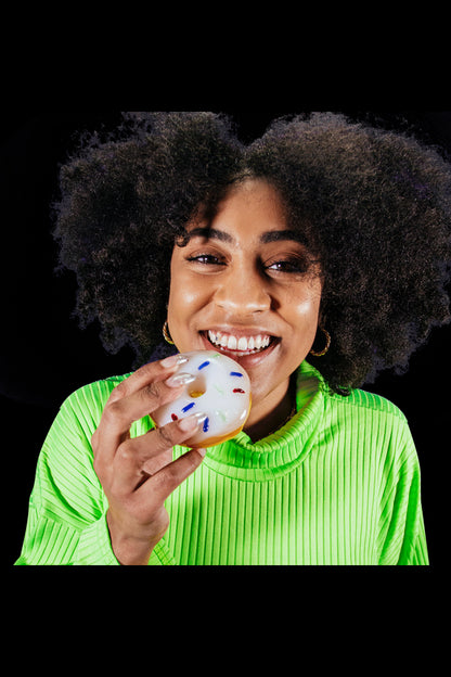 A close-up, front view shows a hand holding the Goody Donut Hand Pipe, resembling a colorful donut.