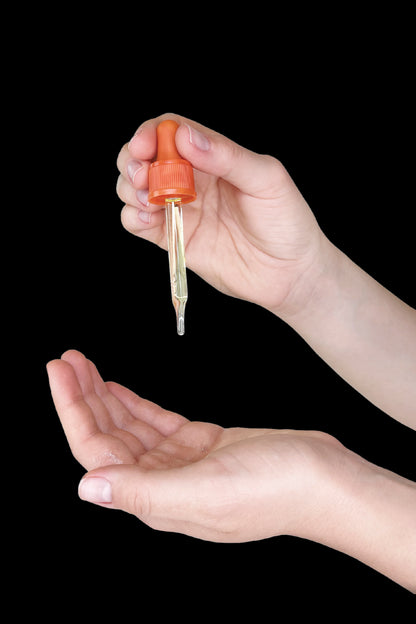 Hand dispensing cannabis oil from a dropper into an open palm.