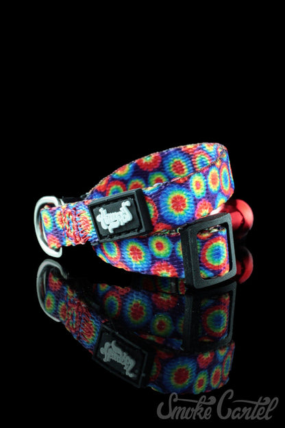 A close-up view of the HeadyPet Cat Collar, showcasing its colorful, patterned design against a dark, reflective surface.