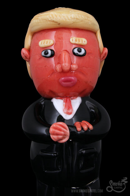 A glass sculpture of Donald Trump wearing a suit, likely a novelty cannabis accessory.