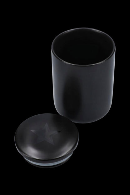 Black cannabis storage jar with lid open beside it.