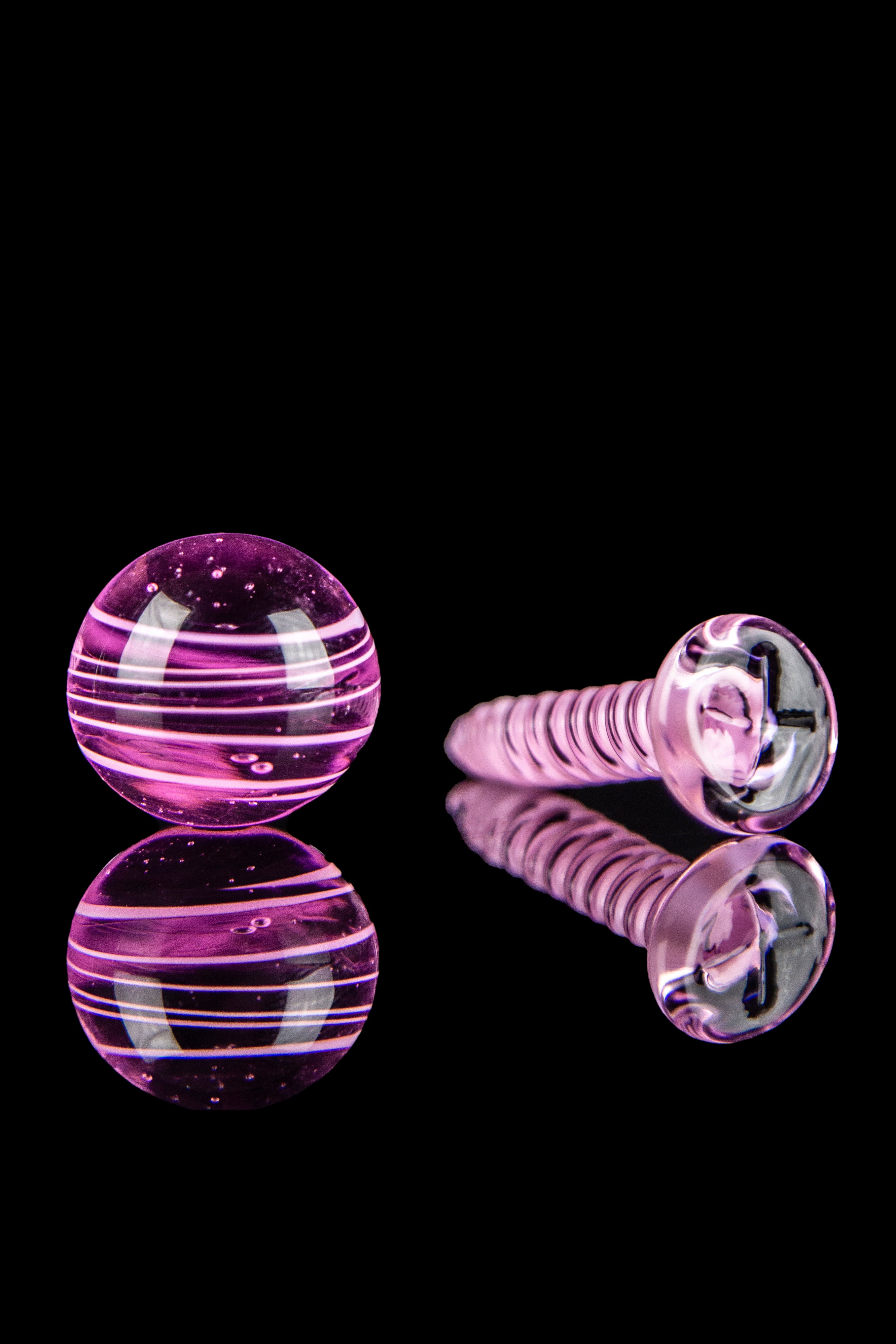 Pink and clear glass cannabis accessories on a reflective surface.