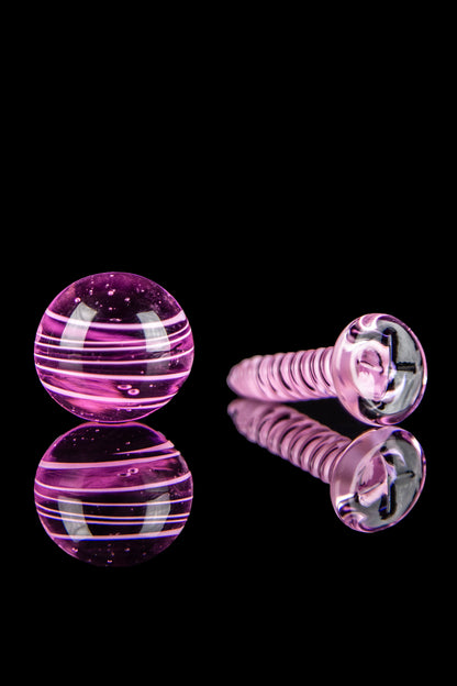 Pink and clear glass cannabis accessories on a reflective surface.