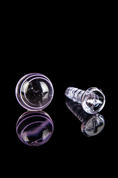 Purple and clear glass cannabis oil rig tips with reflections on a black background.