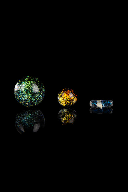 Colorful glass marbles and capsules against a black background, likely cannabis accessories.