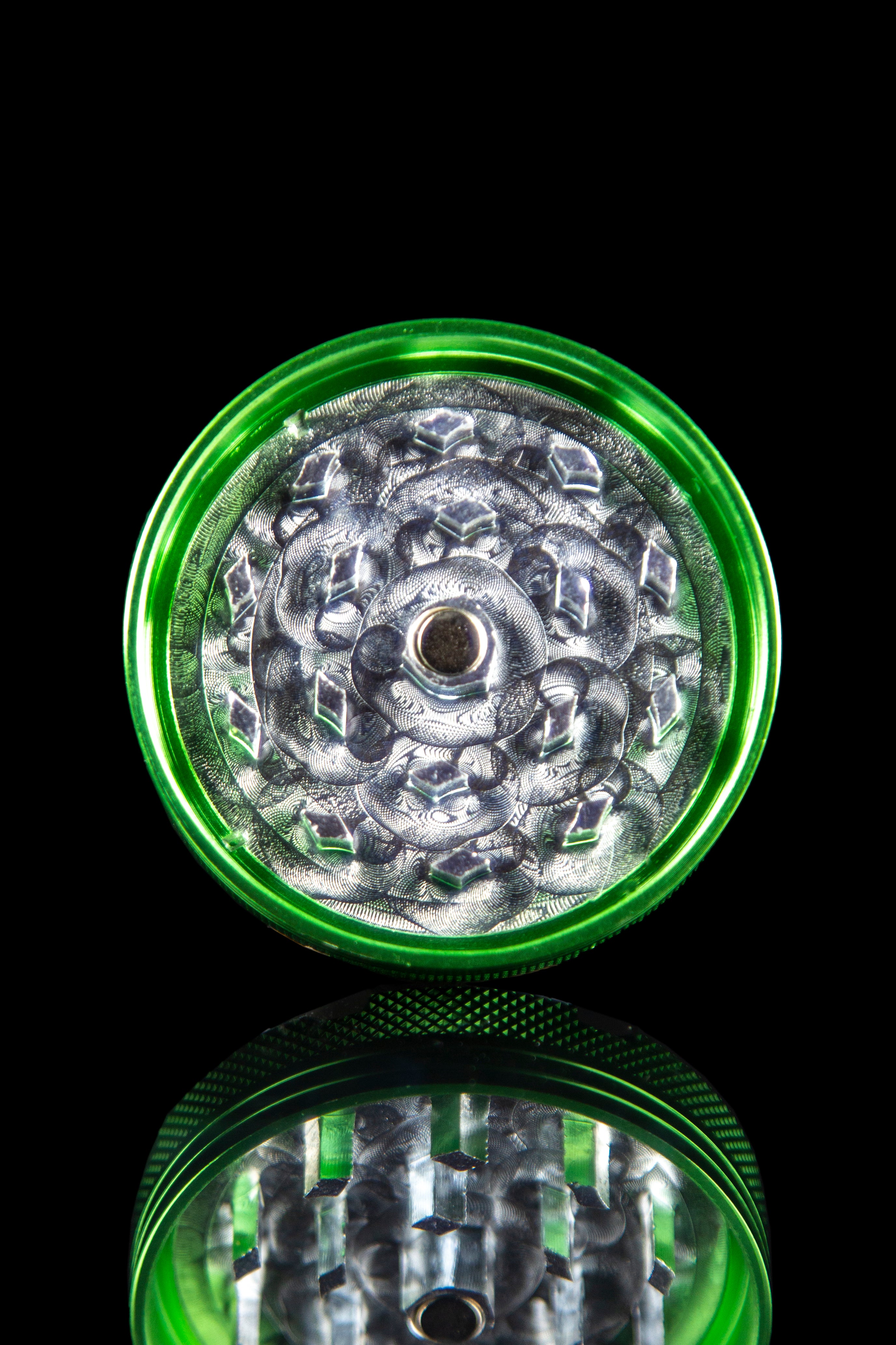 Front view of the Famous X 4-Piece Grinder, showcasing the multi-tiered, metallic grinding teeth against a dark backdrop.