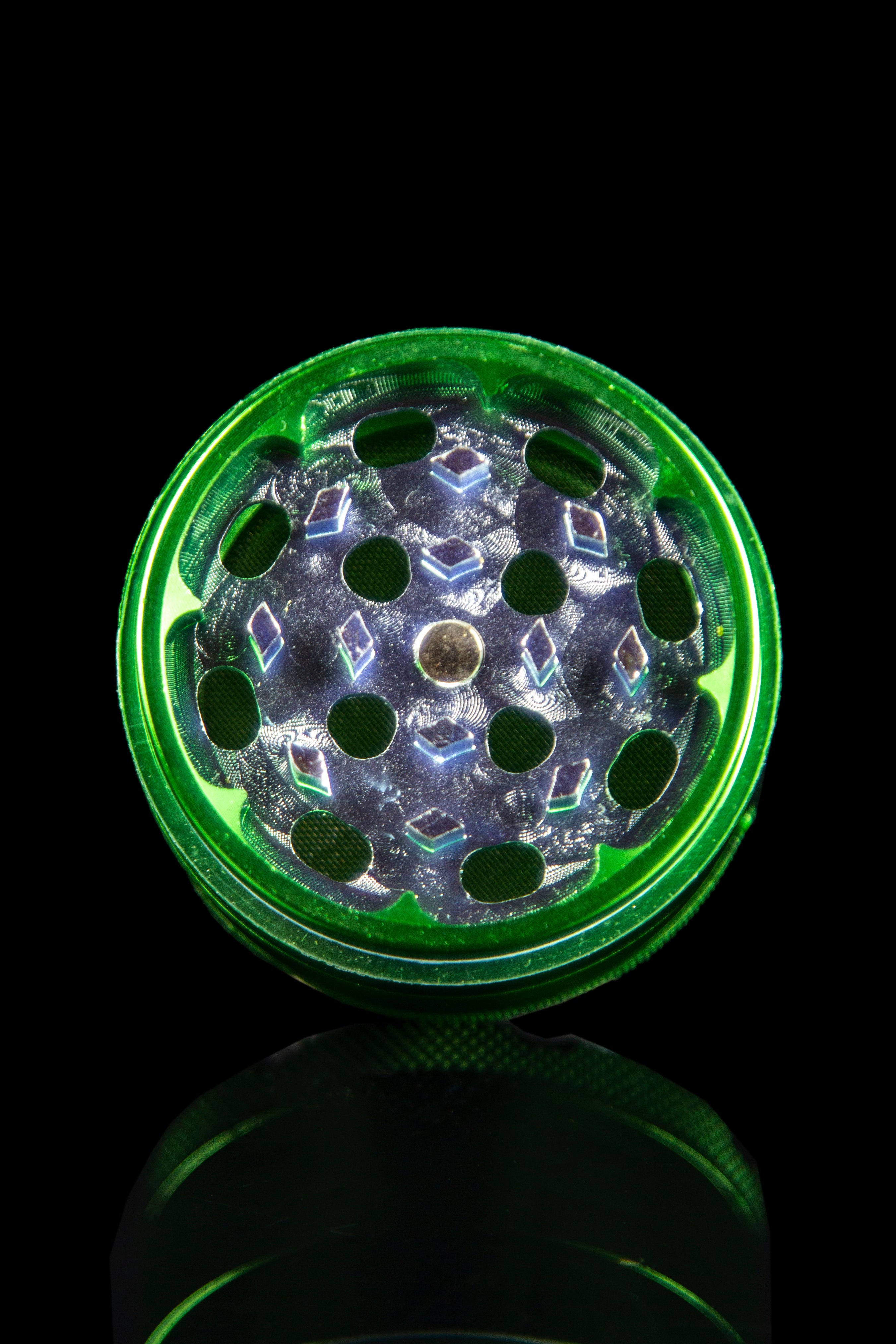 Top-down view of the Famous X 4-Piece Grinder, showcasing its metallic teeth within a circular, dark-toned container.