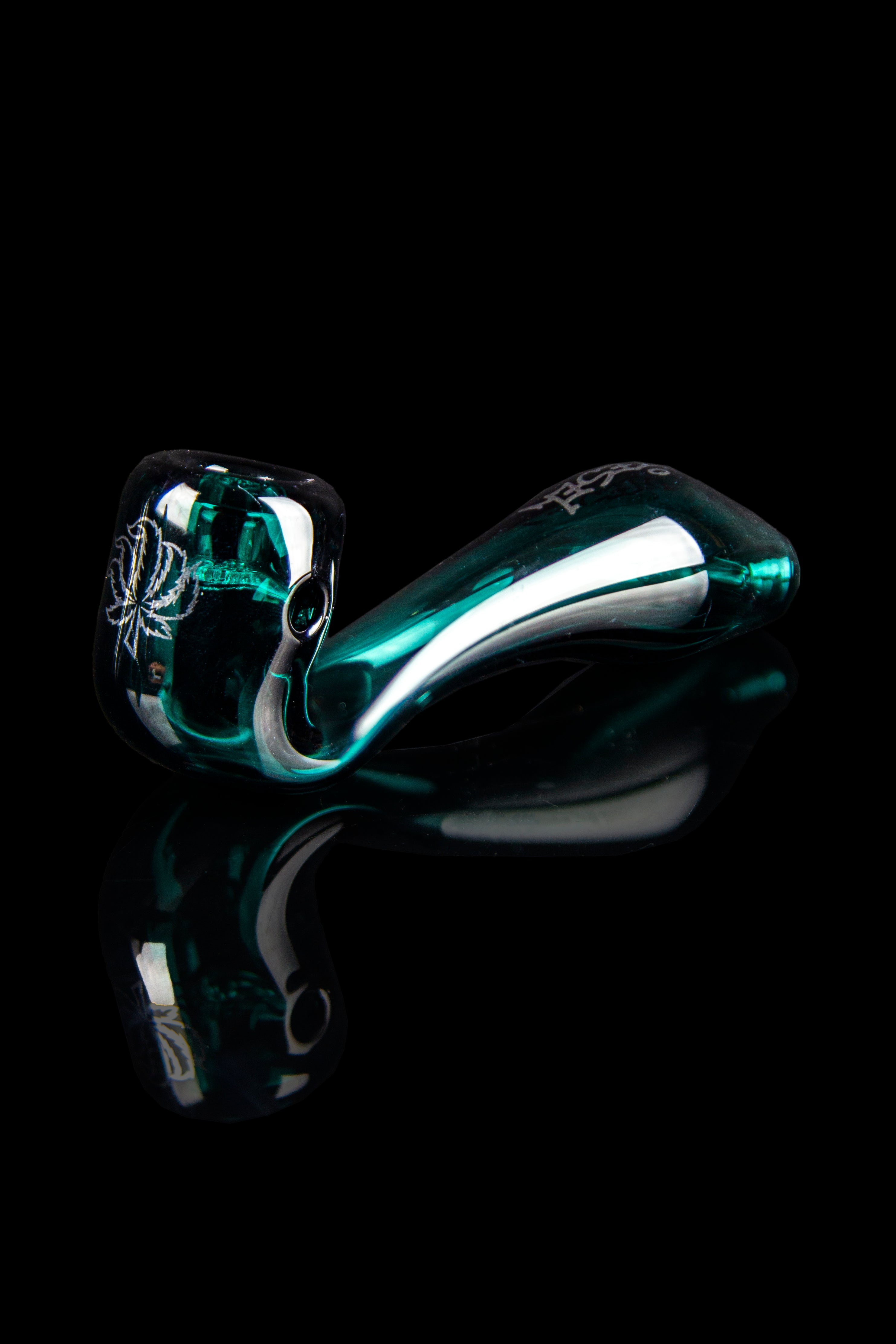 A vibrant teal glass pipe with intricate sculpted details, presented against a stark black background.