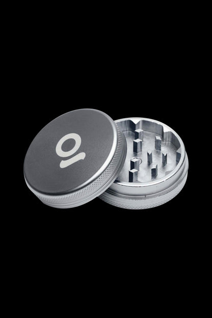 Silver and black cannabis grinder with lid removed, revealing internal grinding teeth.