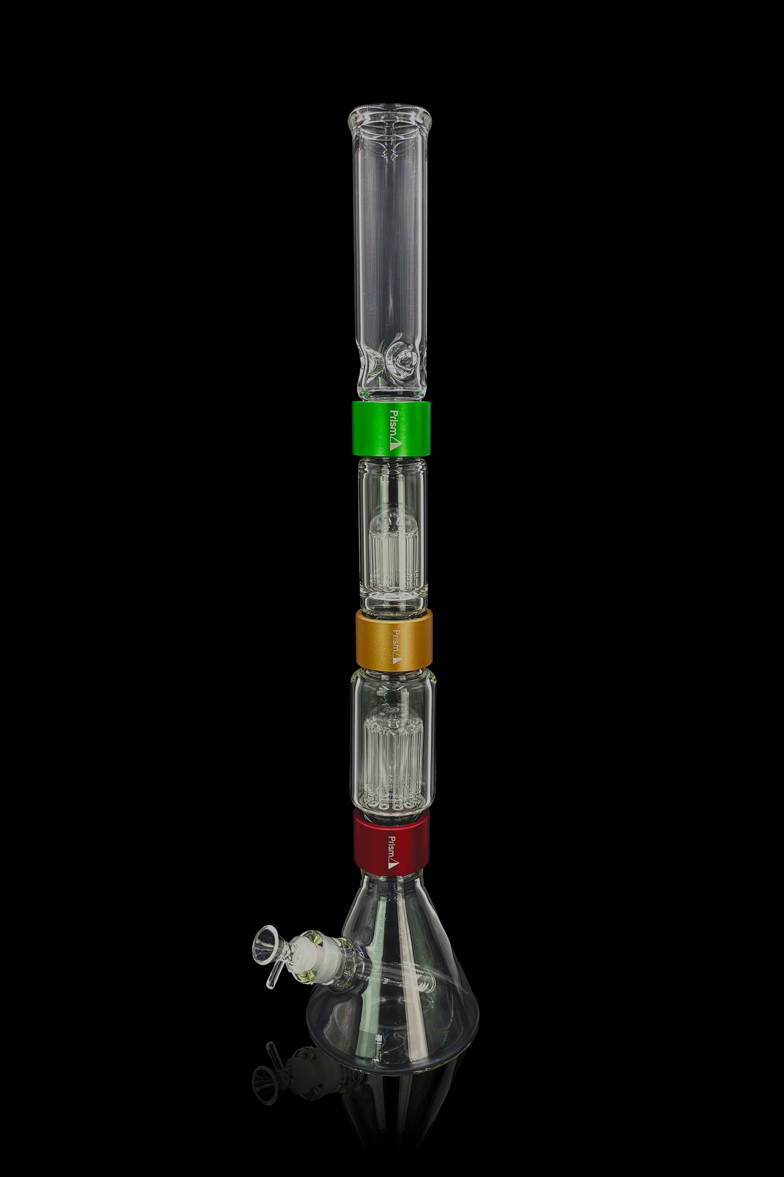 A tall, multi-chambered glass bong with a wide base and visible water, accompanied by a glass bowl and accessories.