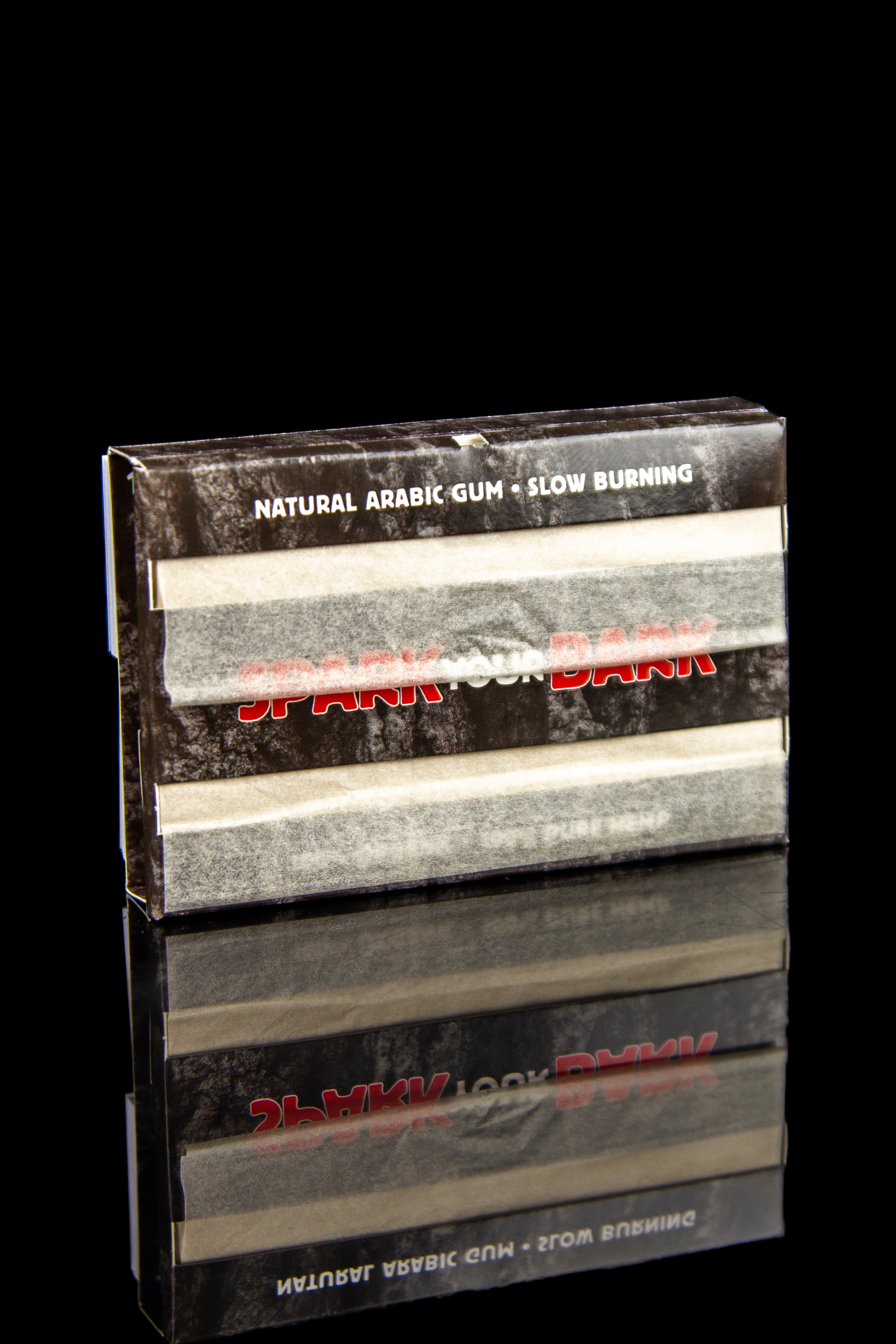 Box of "Slow Burn" natural arabic gum for cannabis joints, reflected on a black surface.