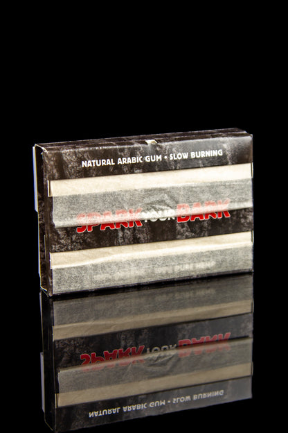 Box of "Slow Burn" natural arabic gum for cannabis joints, reflected on a black surface.