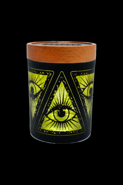 Black glass cannabis storage jar with glowing green all-seeing eye and pyramid design, topped with a wooden lid.