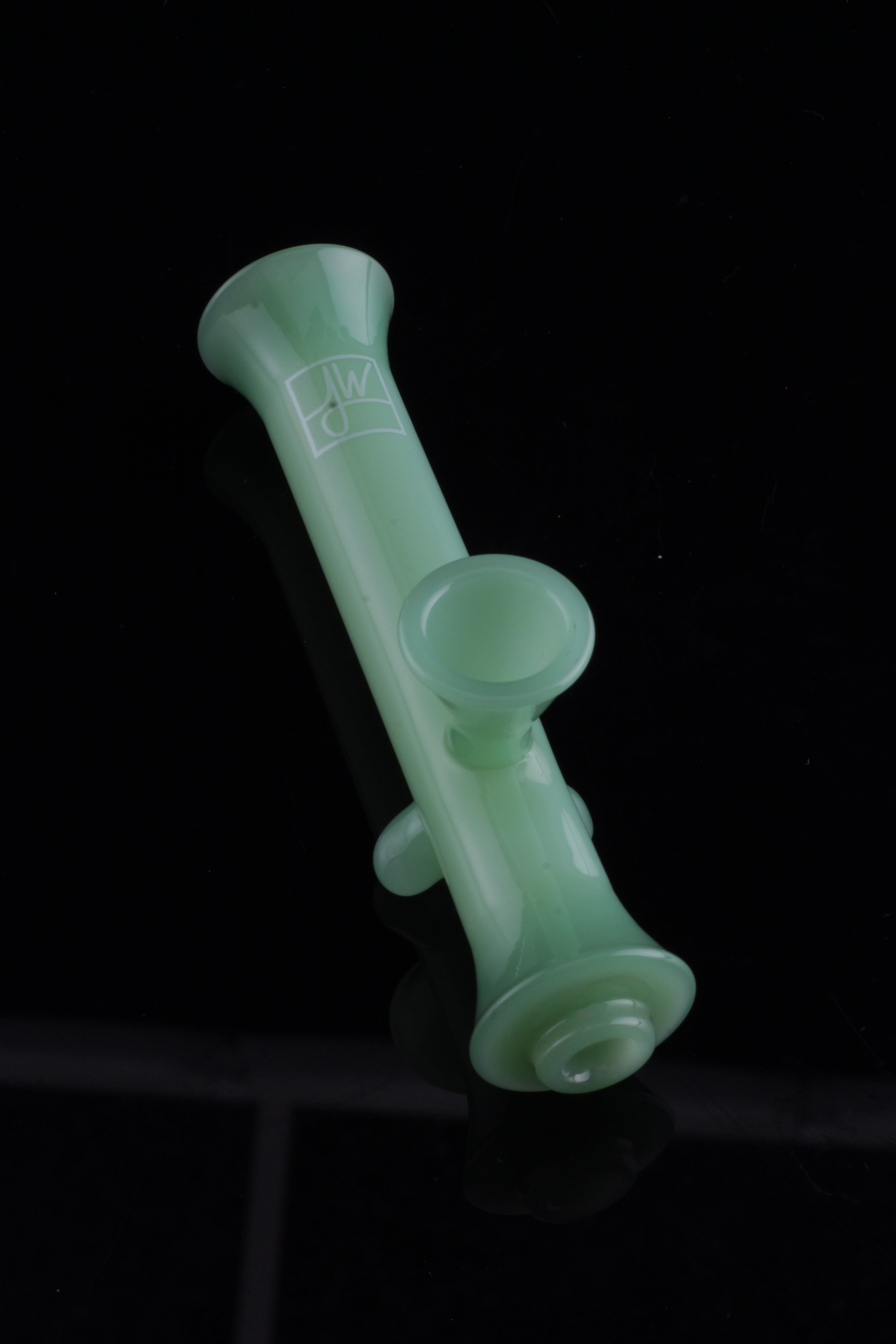 Frosted green glass pipe against a black background.