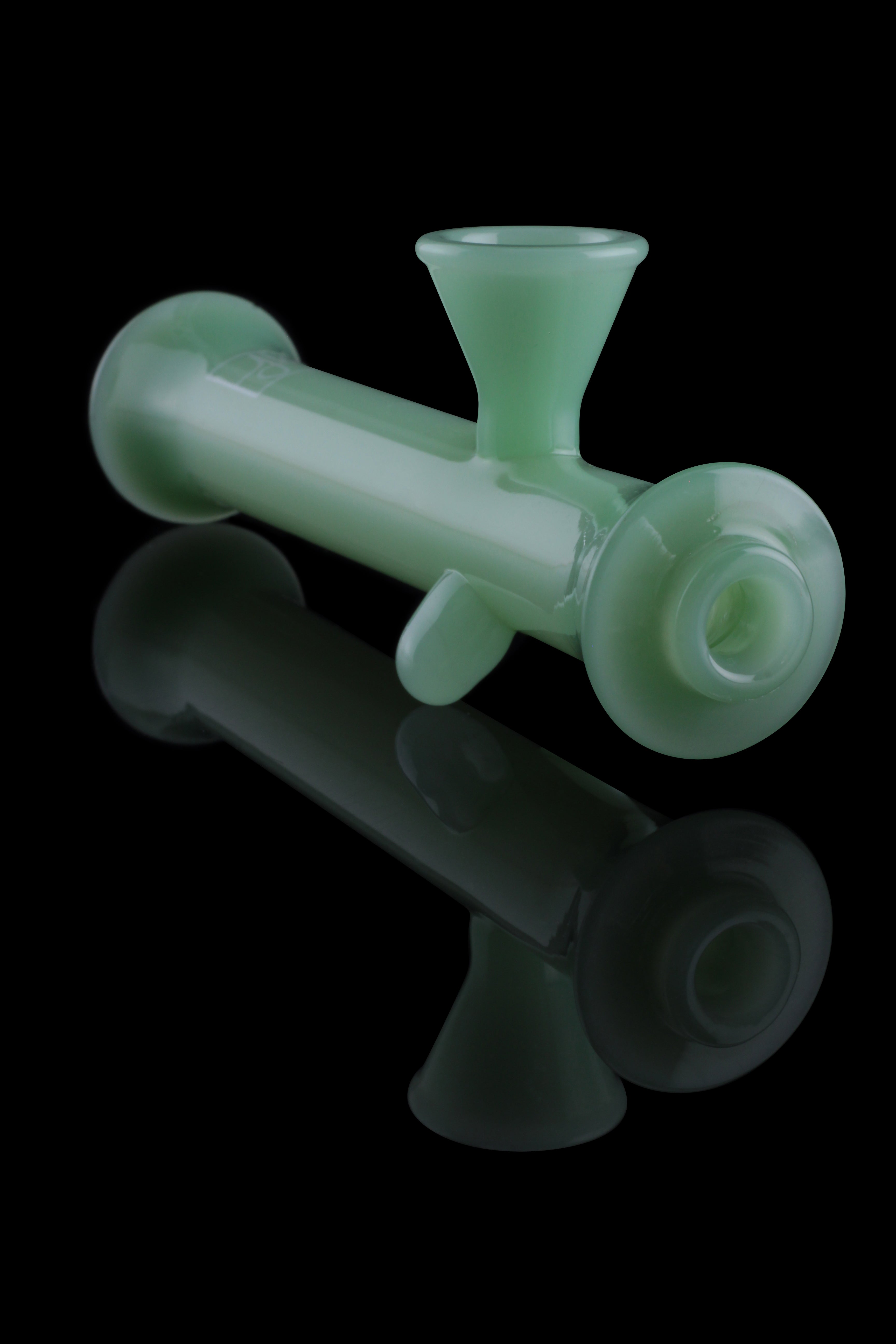 Frosted green glass bubbler with a reflection on a black background.