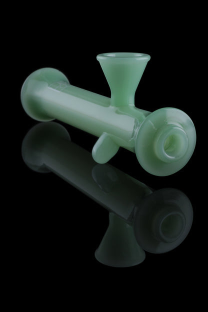 Frosted green glass bubbler with a reflection on a black background.