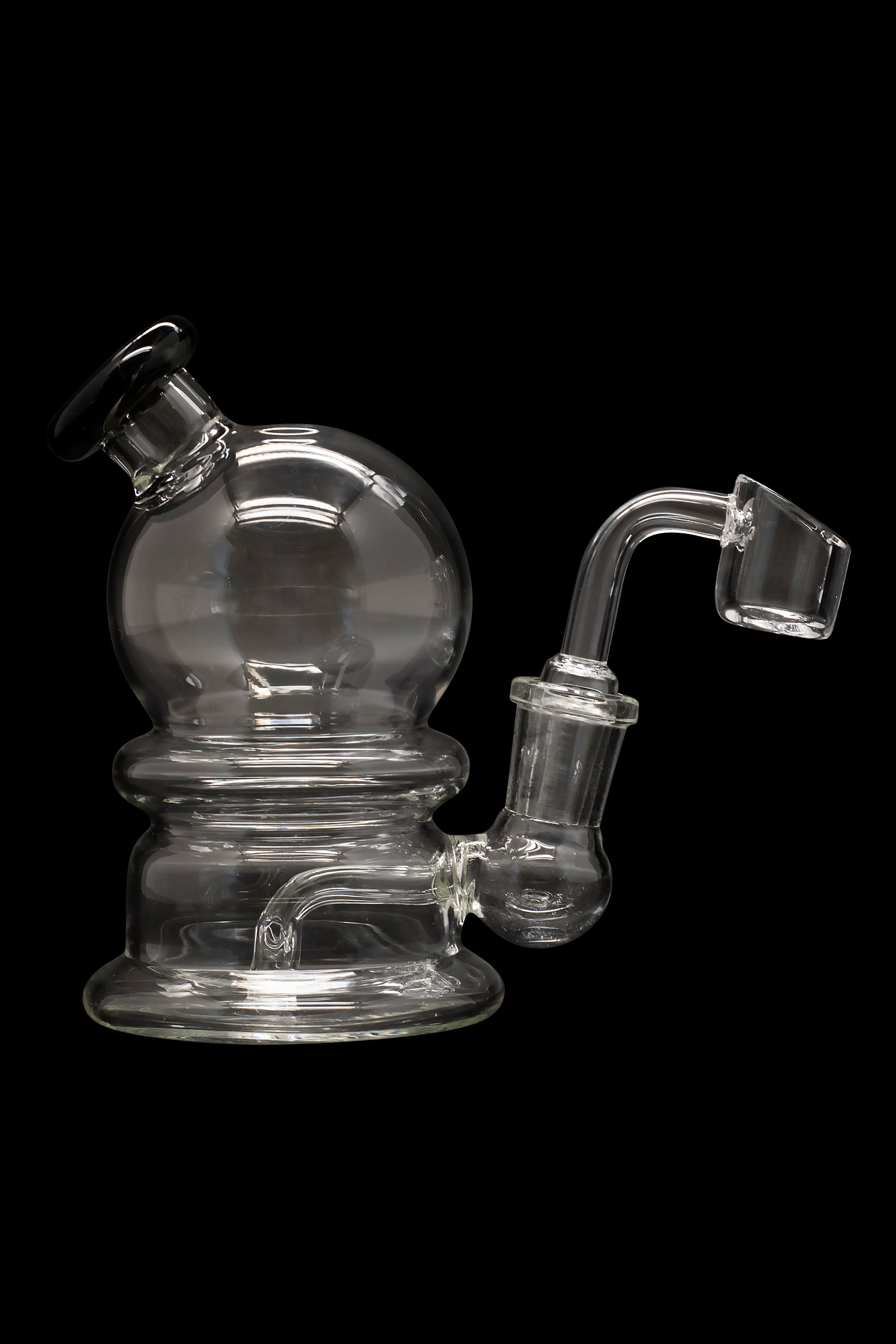 Clear glass dab rig with a spherical chamber and accompanying quartz banger, isolated on a black background.