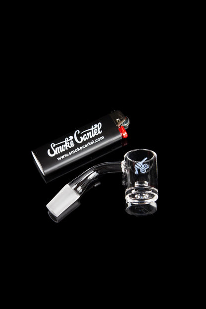 Glass dab rig with skull design, alongside a titanium tip and branded case on a black background.