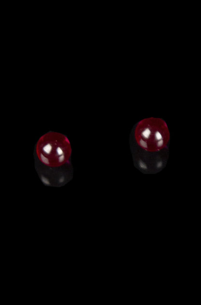 Red glass cannabis pipe screens against a black background.