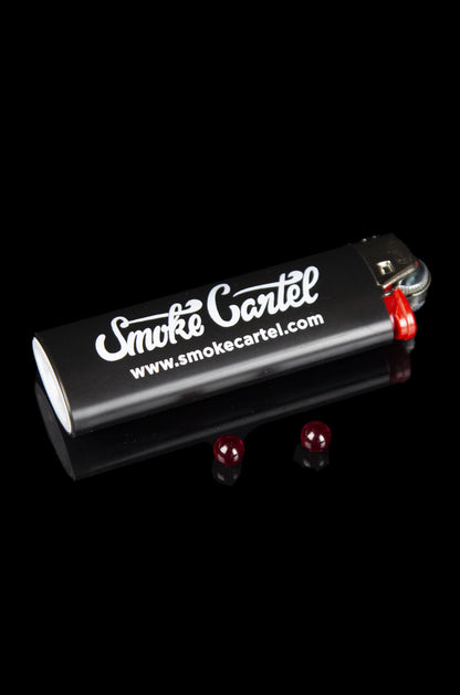 Black butane lighter with “Smoke Cartel” branding and red flame jets, isolated on a black background.